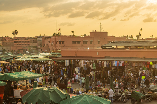 Atmospheric Mood at Djemma el Fna Square in Marrakesh, Morocco, with many people and stalls visible.
