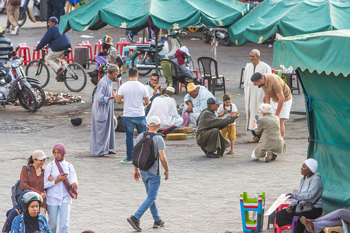 People talking to Snake Charmers at Djemma el Fna Square in Medina District of Marrakesh, Morocco