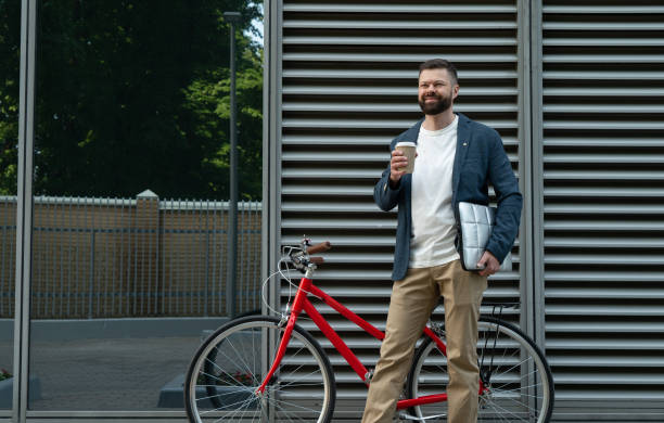 Stylish bearded man with laptop, coffee cup and bicycle