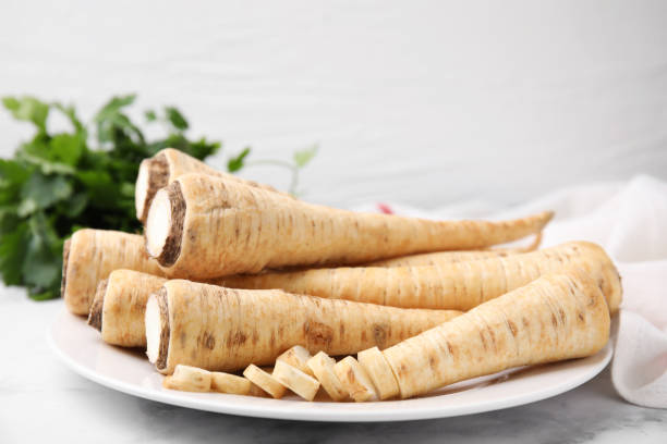 istock Plate with whole and cut parsley roots on white table, closeup 1495216430