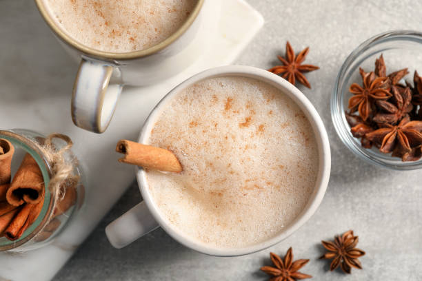 istock Cups of delicious eggnog with anise and cinnamon on light grey table, flat lay 1495216499
