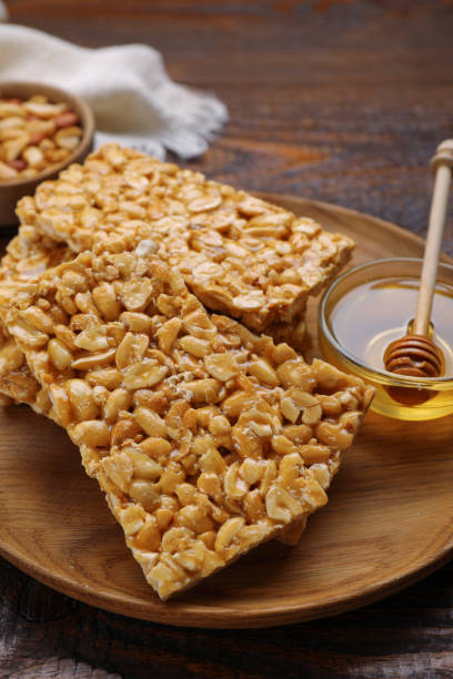 istock Delicious peanut bars (kozinaki) and dipper with honey on wooden table 1495217580