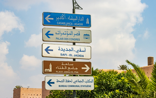 Road Sign in Marrakesh, Morocco, with commercial and government buildings listed.