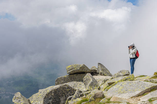 istock Young woman on a high mountain with a photo camera. 1495217632