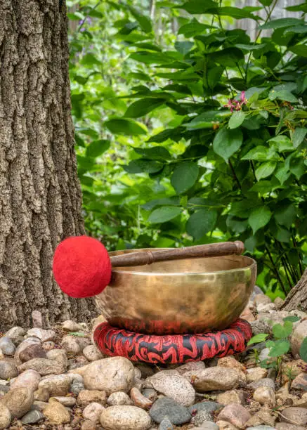 handmade tibetan singing bowl with a mallet and cushion in outdoor setting, sound therapy for healing, relaxation and meditation