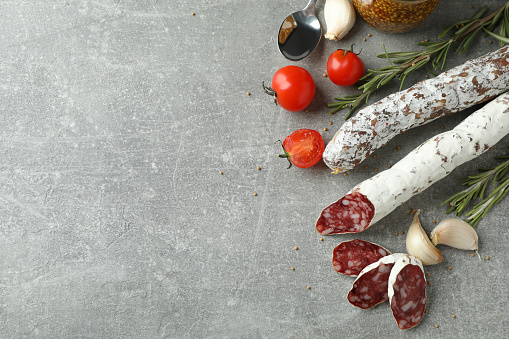 Сoncept of tasty food with salami sausage on gray textured background