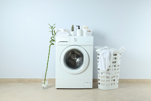 Concept of housework with washing machine against white wall