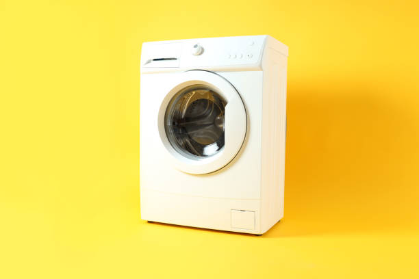 istock Modern white washing machine on yellow background 1495221939