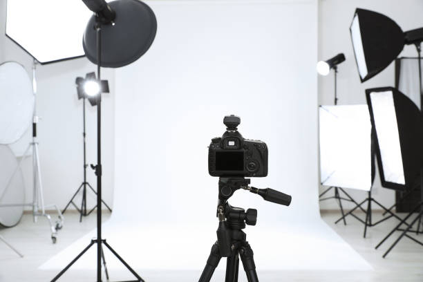 istock Tripod with camera and professional lighting equipment in modern photo studio 1495222986