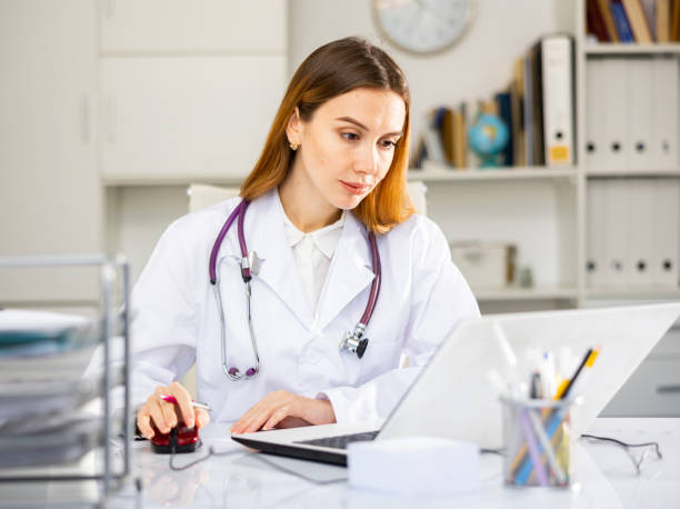 istock Physician woman sitting at table and using laptop 1495224019