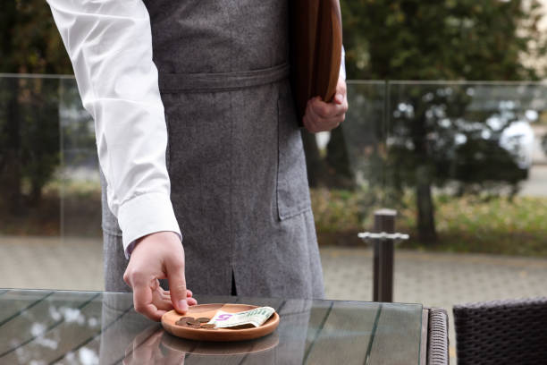 istock Waiter taking tips from wooden table in outdoor cafe, closeup 1495224521
