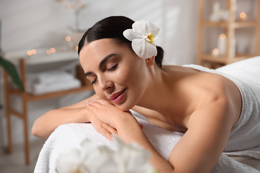 Beautiful happy woman relaxing on massage table in spa salon