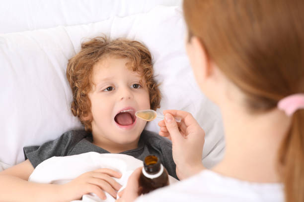 istock Mother giving cough syrup to her son on bed 1495227282