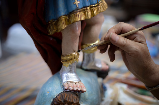 Woman restoring statue of St. Michael