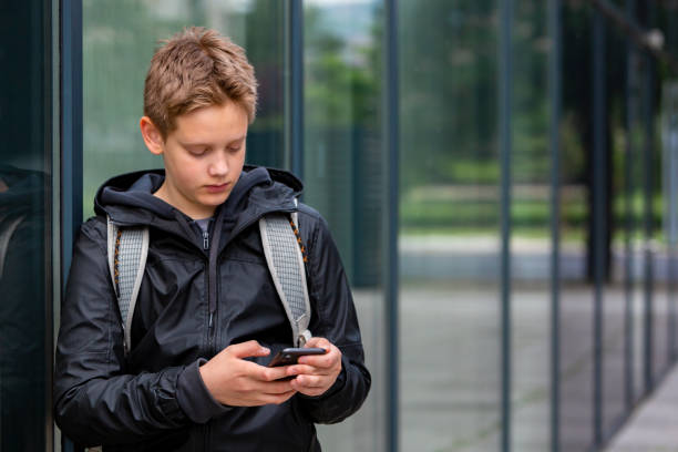Teenage school boy learning using mobile phone stock photo