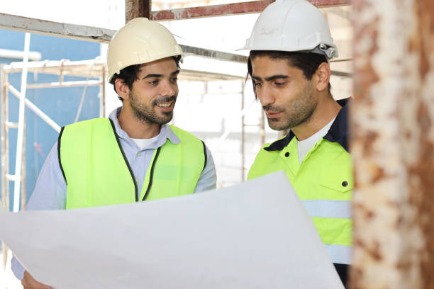 istock Two technician civil engineer or specialist inspector discussing, brainstorm and planing work with laptop, blueprint and walkie talkie radio together at Industrial building site. Construction concept 1495230105