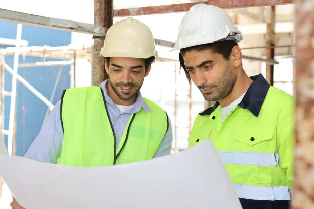 istock Two technician civil engineer or specialist inspector discussing, brainstorm and planing work with laptop, blueprint and walkie talkie radio together at Industrial building site. Construction concept 1495230108