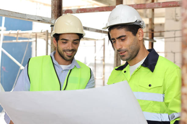 istock Two technician civil engineer or specialist inspector discussing, brainstorm and planing work with laptop, blueprint and walkie talkie radio together at Industrial building site. Construction concept 1495230116
