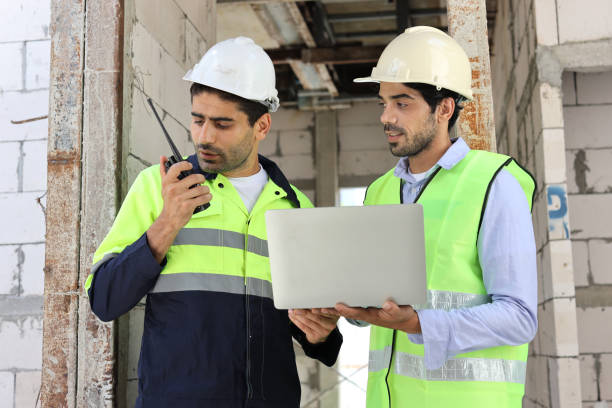 istock Two technician civil engineer or specialist inspector discussing, brainstorm and planing work with laptop, blueprint and walkie talkie radio together at Industrial building site. Construction concept 1495230167