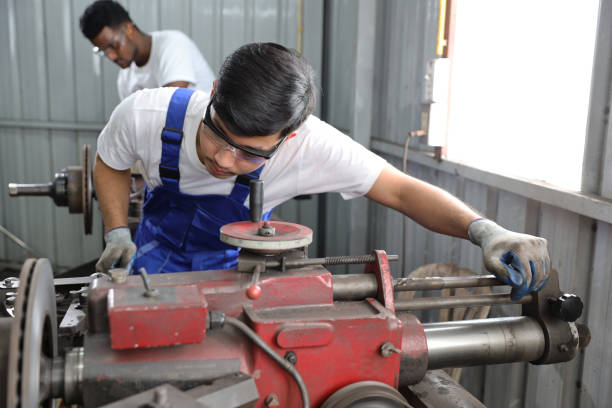 istock Multiethnic technicain mechanic or worker man in protective uniform using metal lathe machine operate polishing car disc brake at garage. Maintenance automotive and inspecting vehicle part concept 1495233231