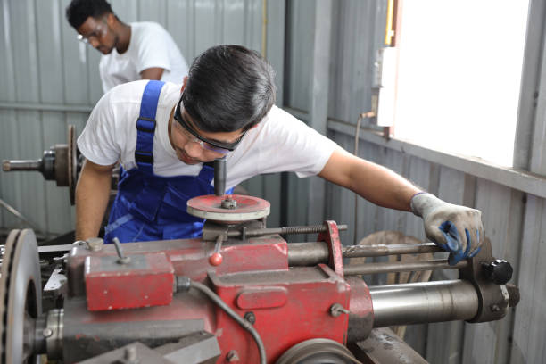 istock Multiethnic technicain mechanic or worker man in protective uniform using metal lathe machine operate polishing car disc brake at garage. Maintenance automotive and inspecting vehicle part concept 1495233233