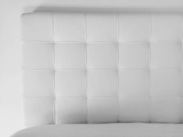 Soft headboard. Upholstery for furniture made of genuine or artificial leather and quilted fabric. Soft headboard against a light wall. Black and white monochrome photo stock photo