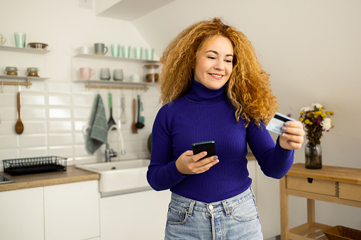 Portrait of a happy young woman using smartphone and shopping online