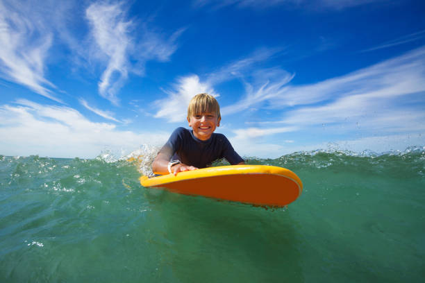 istock Happy boy swim on surf board smiling and looking at camera 1495237235