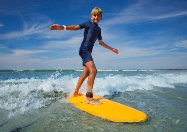 istock Boy learn to stand on the surf board standing at sea beach 1495237255
