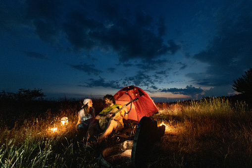 Couple camping in nature with romantic lights and guitar.