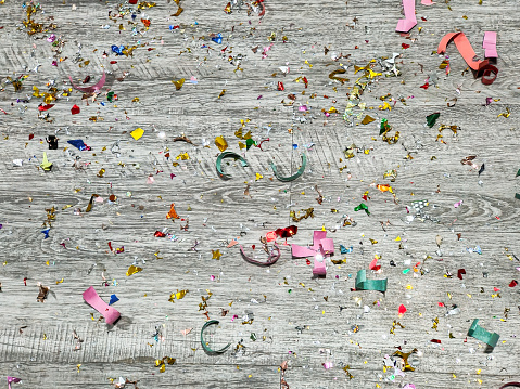 Close-up shot of messy confetti on the wooden floor, after party celebration