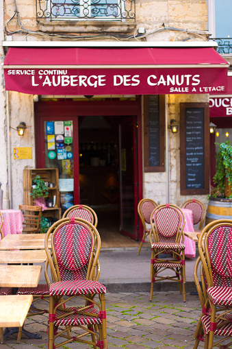 Lyon France: A sidewalk restaurant/brasserie/bouchon with traditional red chairs and awning in sunny Vieux Lyon.