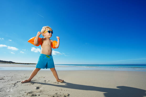 istock Boy stand posing strong and superhero on the ocean beach 1495246558