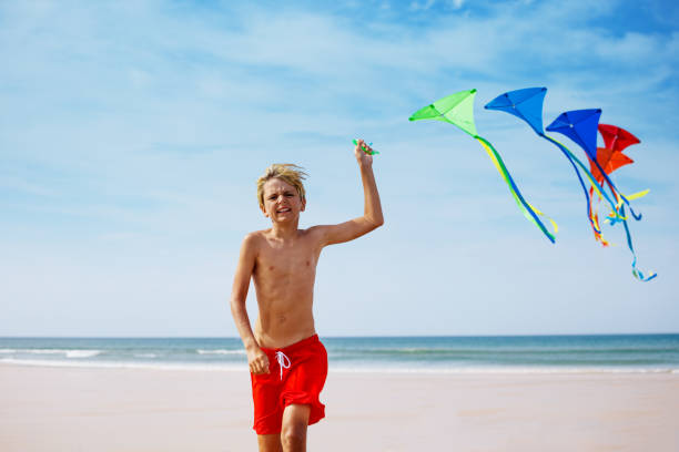 istock Close boy run on the beach holding a colorful kite group 1495246604