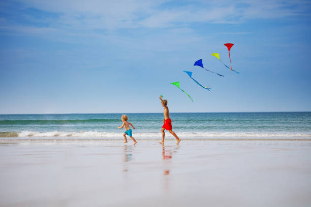 istock Boys run holding many colorful kite at beach smiling side view 1495246605