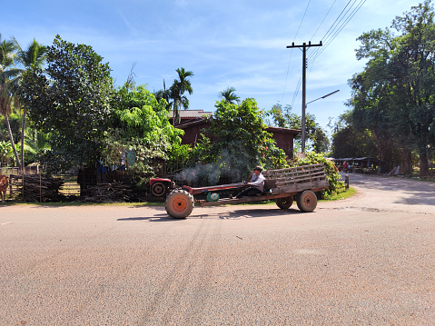 Local man riding a two-wheel tractor in Champasak province, Southern Laos.
