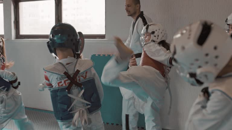 A group of children of different ages train under the supervision of a martial arts coach