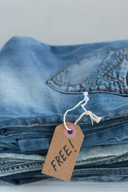 istock Stack of blue jeans and tag with inscription free on white background 1495248685