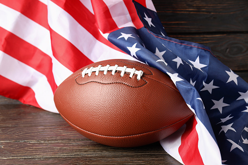American football ball and American flag on wooden background
