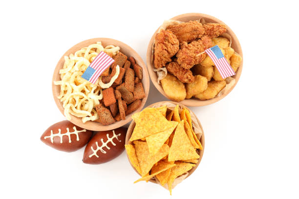 Close up of chicken wings with sour cream and chips with a football and balloons in the background, taken on top of astroturf; it's a championship game party; copy space 