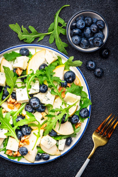 istock Gourmet salad with sweet pears, blueberries, blue cheese, arugula and walnuts. Black table background, top view 1495253299