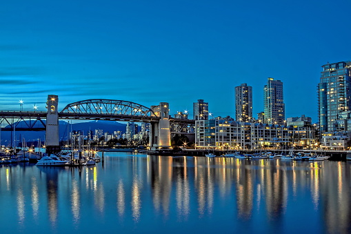 Vancouver Canada, Burrard Bridge and downtown Vancouver at night, reflection of the city's night lights in the mirror water of the bay, shot done from Granville Island