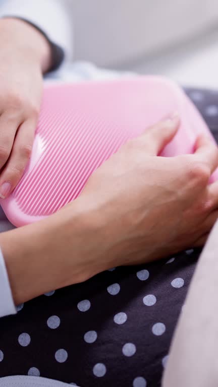 Young Woman With Hot Water Bottle On Stomach Lying