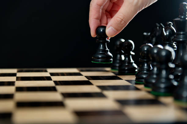 Human hand holding chess pawn.