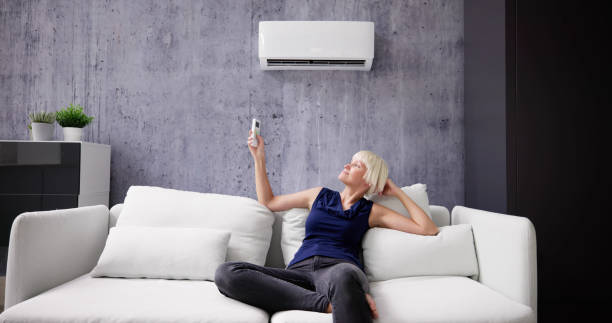 istock Happy Young Woman Holding Remote Control Relaxing Under The Air 1495275780