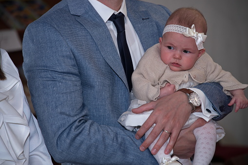 Midsection of father holding his baby girl in a church ready for christening