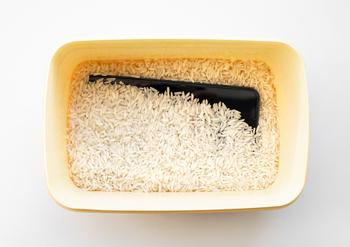 Water or liquid damaged smartphone dry inside box filled with uncooked white rice which supposed to absorb moisture but some say rice dust can harm device.