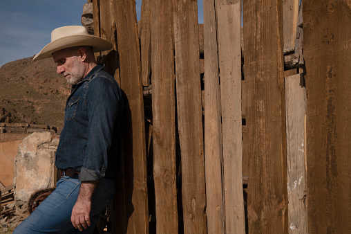 Portrait of adult man in cowboy hat against wooden wall