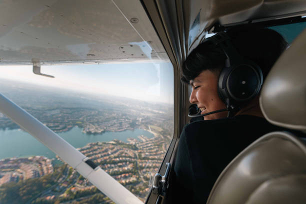 A young boy sits on the airplane, happily gazing out of the window, feeling extremely content.