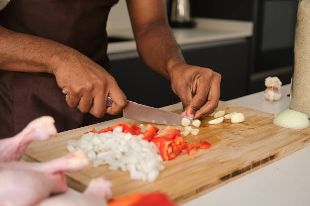 Unrecognizable young black man cutting garlic.